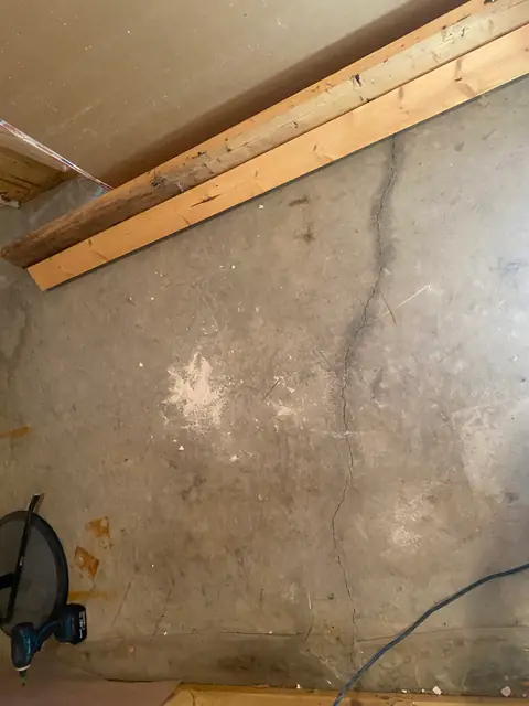 Vertical crack visible on a concrete wall beneath timber framing
