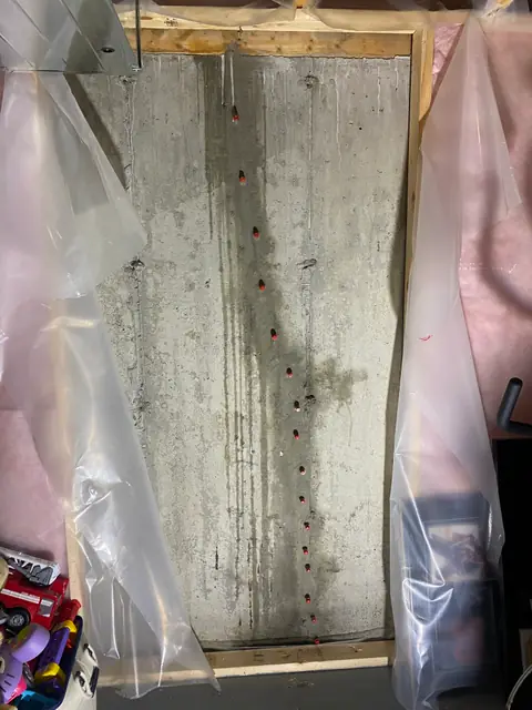 Exposed concrete wall between framing with protective plastic sheeting at the sides