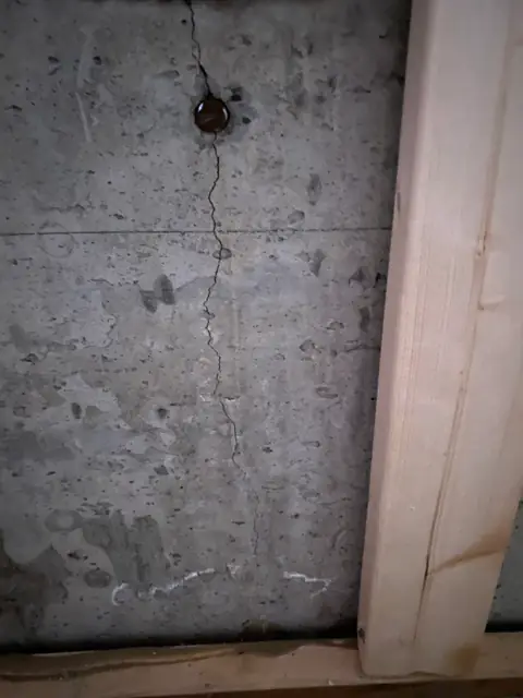 Vertical concrete crack inside a rectangular opening in a finished wall