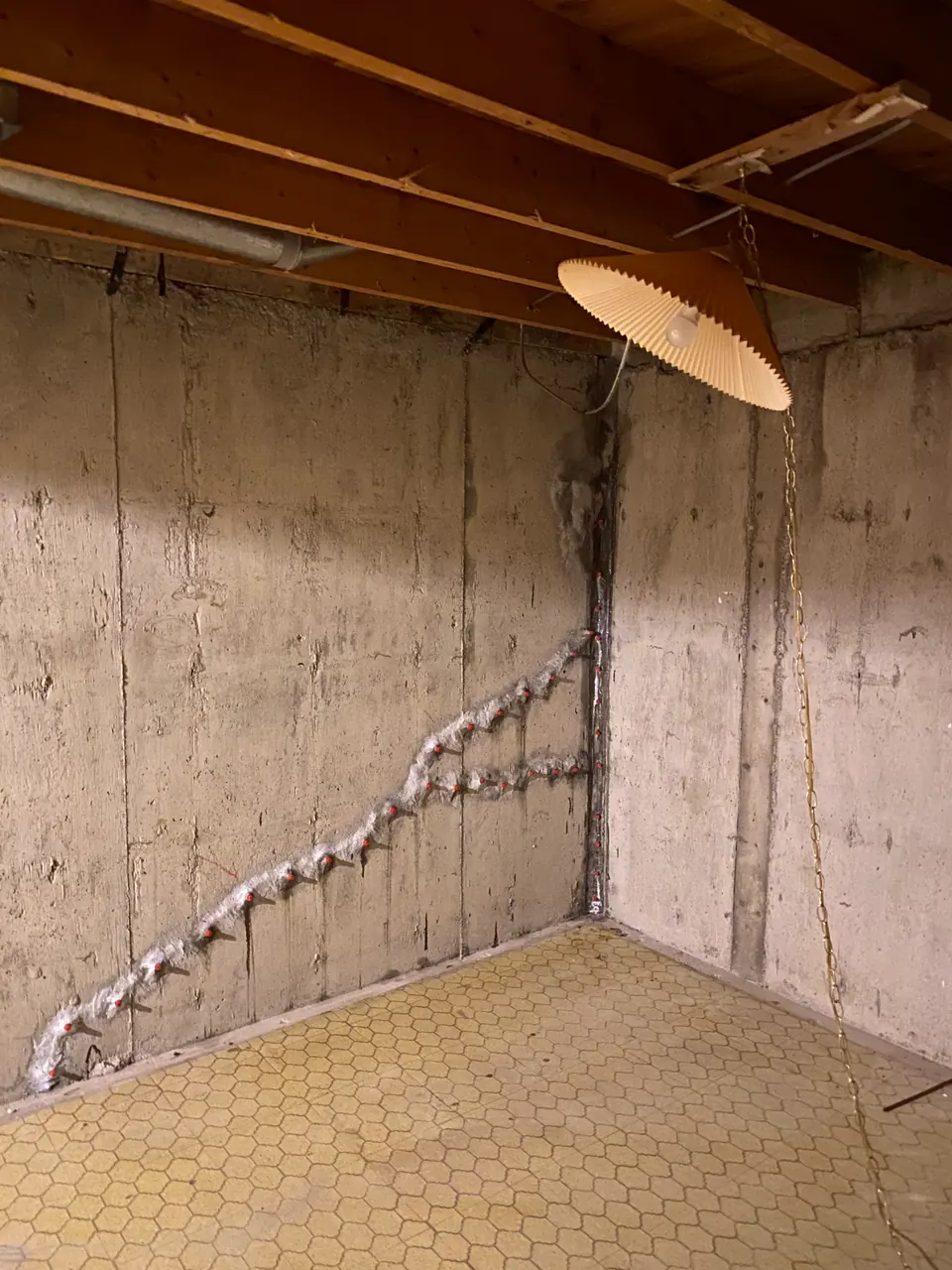 Diagonal crack line with white surface material on an exposed basement wall