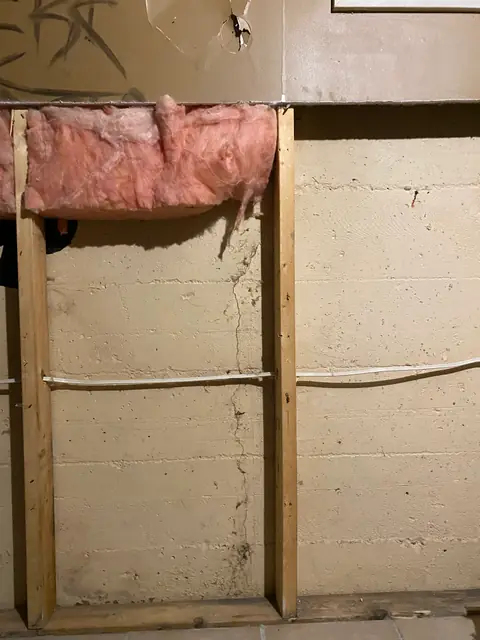 Exposed concrete and timber framing beneath an opened section of insulated wall