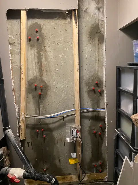 Red-capped repair points on a concrete wall between timber studs