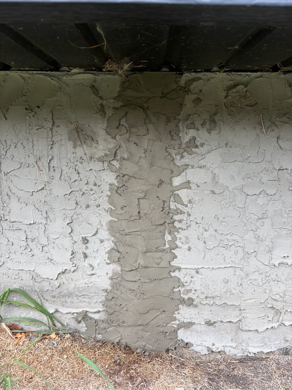 Exterior foundation wall with a vertical patched area above the ground