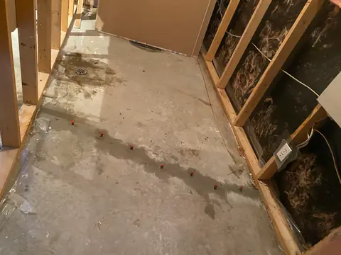 Concrete floor with a darker line beside exposed timber wall framing
