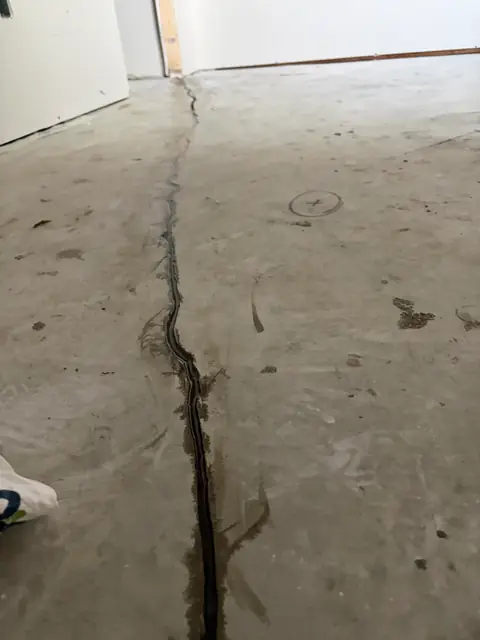 Long crack in a concrete floor leading toward a doorway