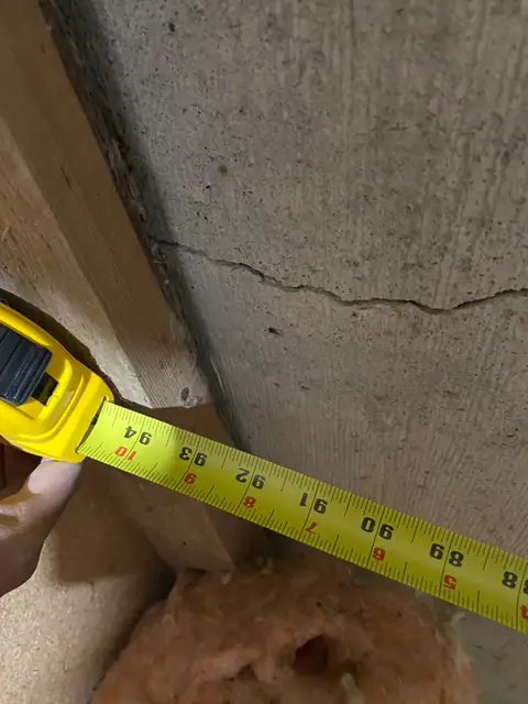 Tape measure beside a timber stud and a horizontal crack in concrete