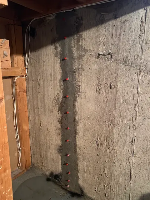 Red-capped repair ports along a vertical concrete wall line beside timber framing