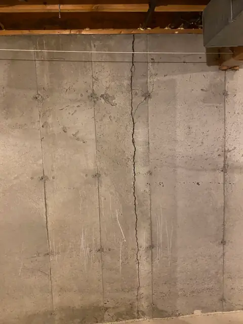 Full-height vertical crack on an exposed concrete basement wall