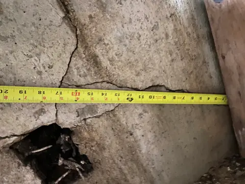 Horizontal tape measure across cracks in an exposed concrete wall