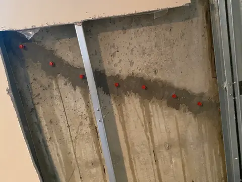 Horizontal surface repair with red ports on a wall behind metal framing