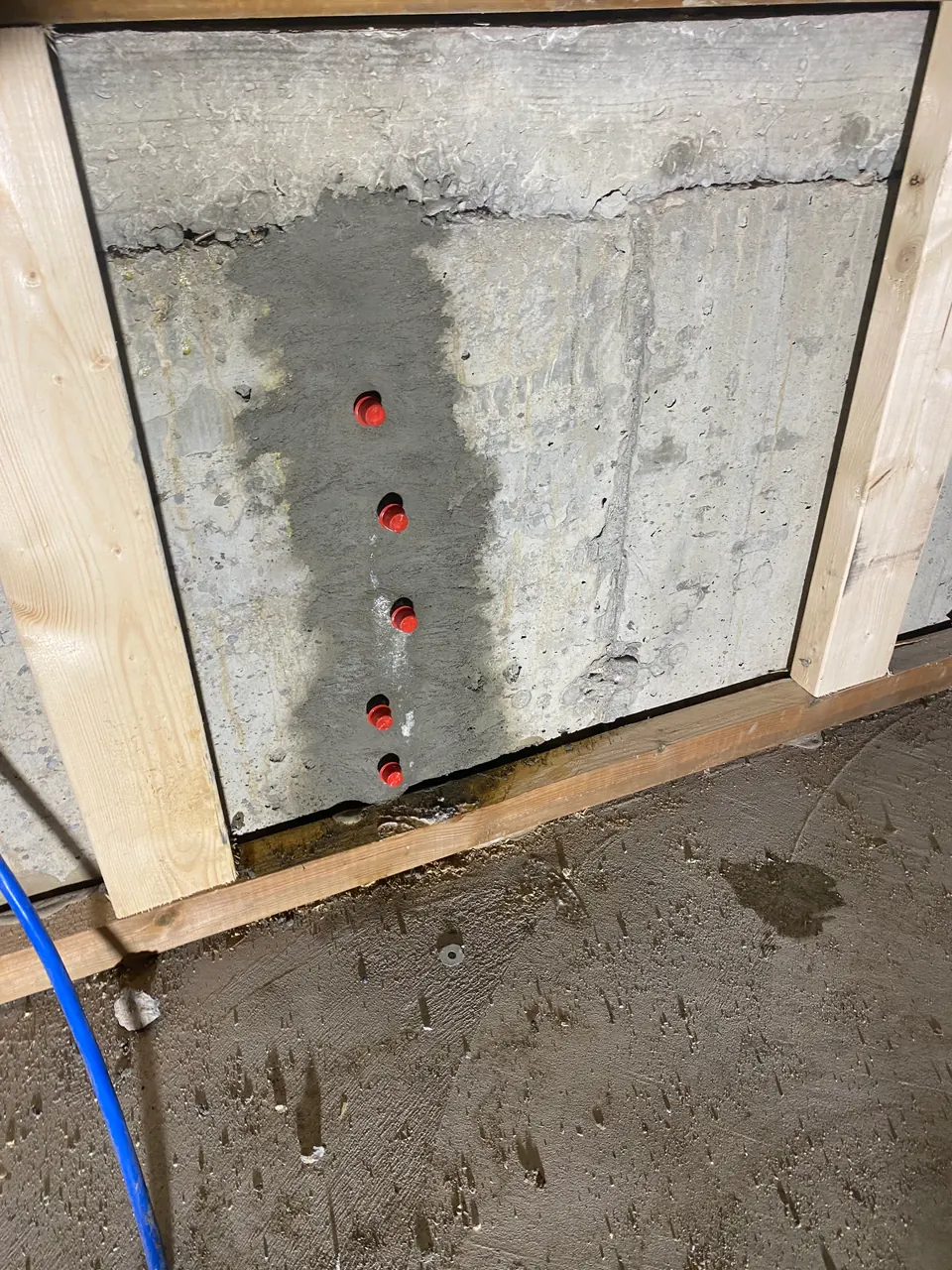 Red repair ports along a prepared vertical crack inside an opened wall panel