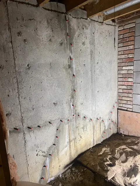 Repair ports on several concrete crack lines beside a brick wall return