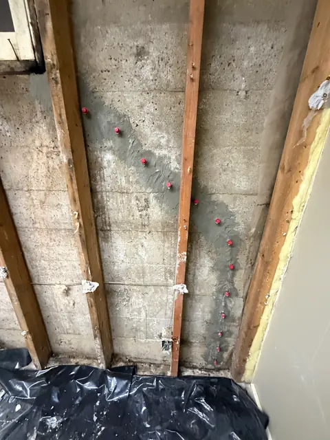 Red repair ports along a prepared crack between exposed timber wall studs