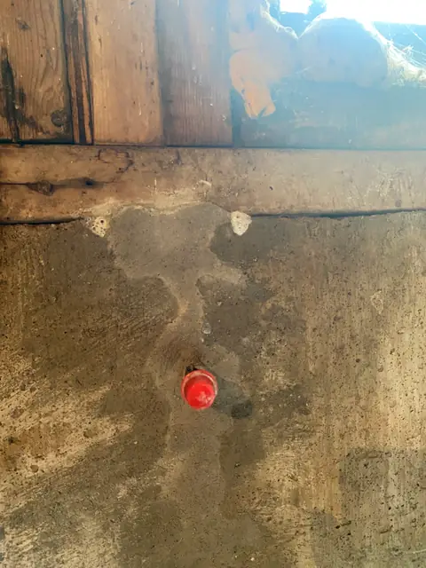 Red-capped repair port in a prepared concrete patch below timber framing