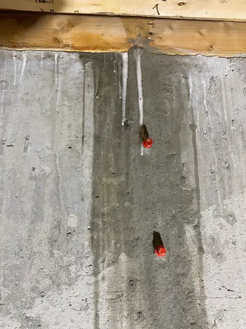 Two red-capped ports in a prepared concrete area below timber framing