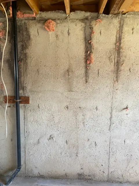 Vertical crack on an exposed concrete wall beneath timber floor joists