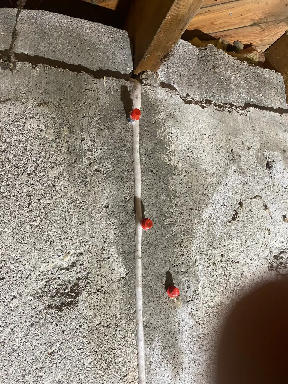 Red-capped repair ports on a prepared vertical concrete crack beneath floor framing