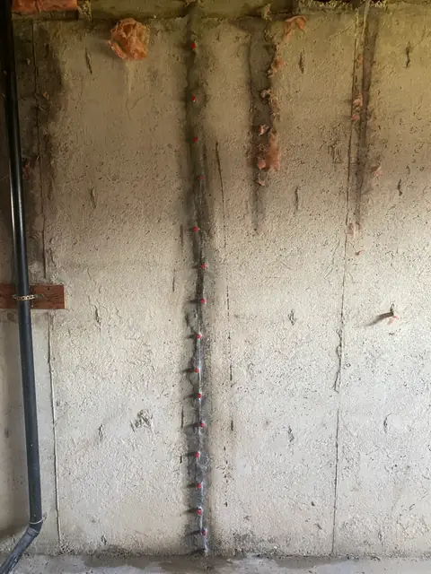 Close view of a vertical concrete wall crack with openings along its length