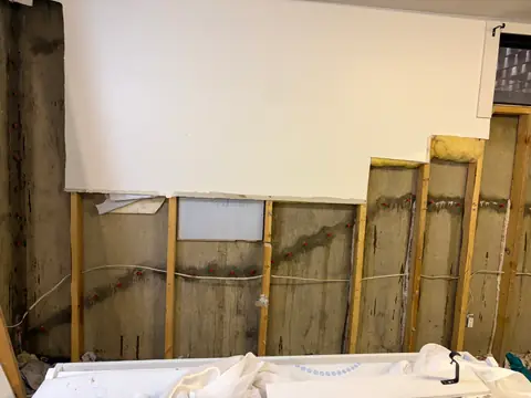 Opened wall finish following a stepped edge with framing and concrete exposed