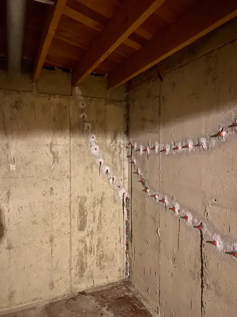 Repair ports and white surface material on exposed concrete near a wall corner