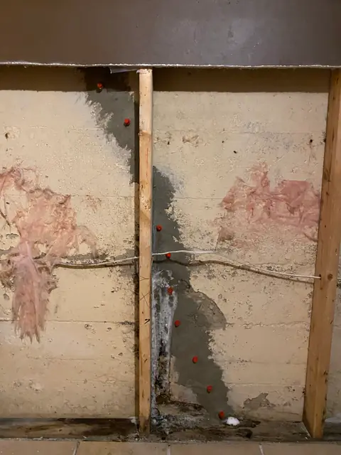 Vertical surface repair with red ports between timber wall studs